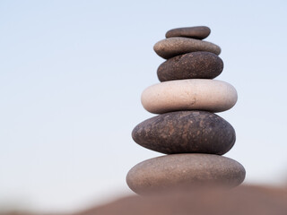 A stack of smooth stones forms a balanced tower against a serene backdrop, tranquility and harmony by soft lighting. Cairn, stones balances, pyramid of stones, concept of life balance