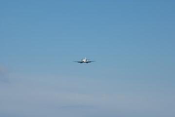 An airplane in flight gliding through an expansive blue sky with minimal cloud coverage