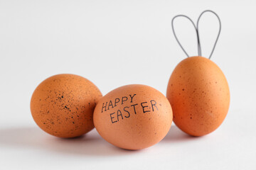 Chicken eggs with text HAPPY EASTER and bunny ears on light background