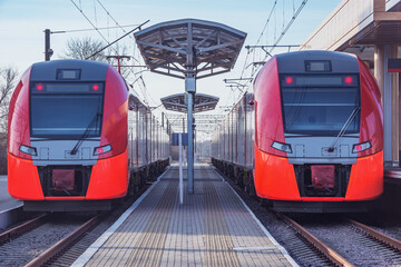 Obraz premium Two trains stand by the platform.