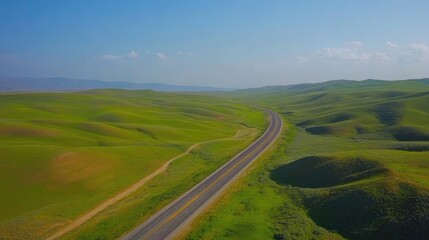 A highway through rolling green hills, stretching endlessly with blue skies above