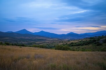Fototapeta premium Serene Landscape of Rolling Hills and Mountains Under a Soft Evening Sky in Tranquil Rural Setting