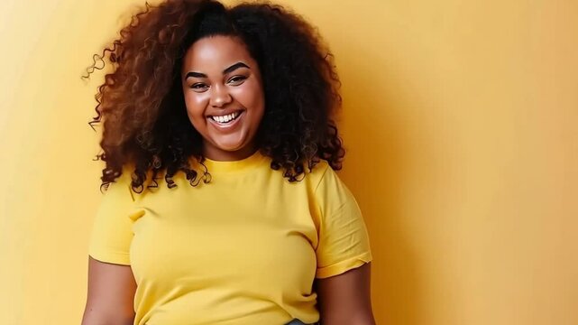 portrait of happy and smiling young plus size woman isolated on yellow background, positive person having fun and dancing
