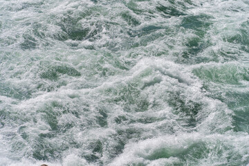Frozen splashing in rapids of powerful mountain river,water background