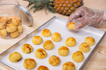 Hand Picking Freshly Baked Nastar Cookies from Tray to Glass Jar