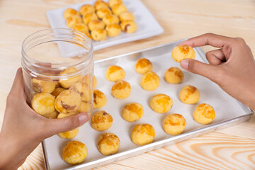 Hand Picking Freshly Baked Nastar Cookies from Tray to Glass Jar
