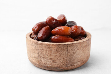 Tasty dried dates in wooden bowl on white table, closeup