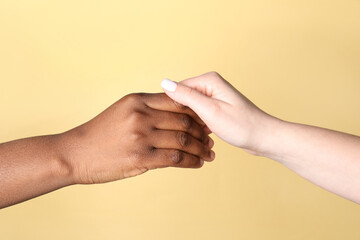 Stop racism. People of different skin colors holding hands on beige background, closeup