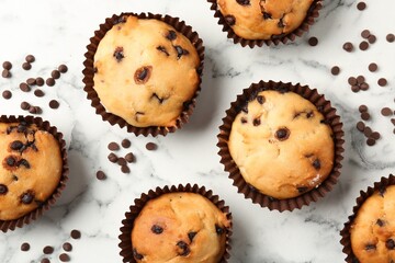 Delicious muffin with chocolate chips on white marble table, flat lay