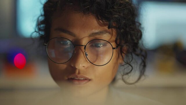 Closeup of an intelligent woman coding at night, digital light accentuates her tech expertise.