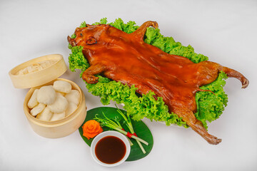 A whole roasted suckling pig with crispy golden-brown skin, served on fresh lettuce, accompanied by...