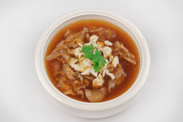 A bowl of rich brown soup with shredded meat, mushrooms, and crab meat, garnished with a sprig of cilantro, served in a white ceramic bowl.