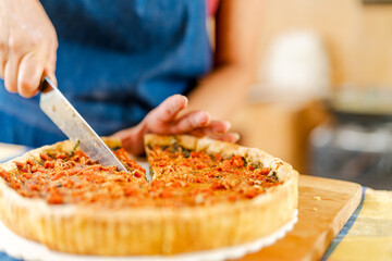 Chef cutting savory spinach and bacon quiche with knife