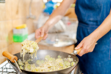 Chef cooking leeks in wok with steam rising