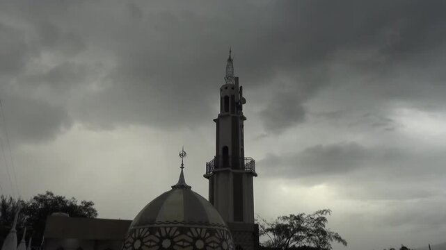 a mosque tower timelapse with thick clouds and moderate rain in malang city