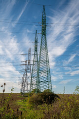 High voltage power lines and power pylons in the agricultural field. Electricity distribution.