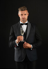 Elegant tuxedo man hold glass of champagne isolated on black. Celebrating success. Cheers. Tuxedo man look formal. Celebrate with champagne. Cheering and celebrating. Man in tuxedo
