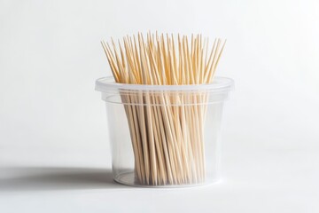 Numerous Light Brown Wooden Toothpicks in Clear Plastic Cup on White Background