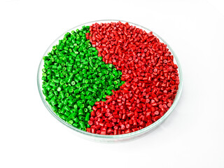 Green and red  masterbatch plastic granules in aluminum cup, polymer carrying pigment poured into...