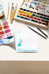 Paper And Palette Of Watercolor Paints On The Desk.