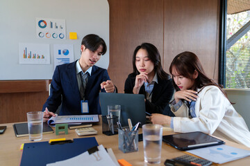 Young startup professionals discussing business data on a laptop, analyzing financial growth and marketing strategies in a modern collaborative workspace for innovative decision-making