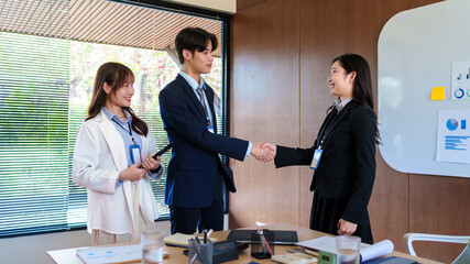 Confident young business professionals shaking hands to finalize a successful deal, celebrating partnership and agreement in a collaborative startup office environment