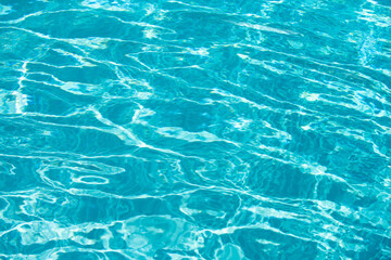 Water background, ripple waves. Blue swiming pool pattern. Sea surface. Water in swimming pool with sun reflection. Banner with copy space.