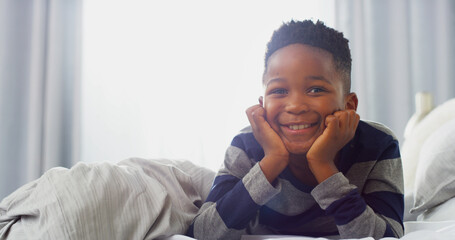 Portrait, happy child and African boy in bedroom for relax, calm or wake up on weekend break. Face,...