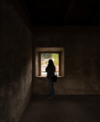 Silhouette of woman looking through window in historic site, La Antigua, Guatemala