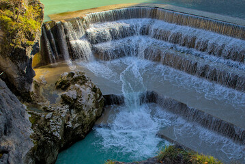 The Lech River in Fussen, Germany, gracefully descends in a series of man-made steps. The rushing...
