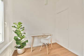 A serene and bright interior featuring a simple wooden desk, a modern chair, and a leafy plant by the window, creating a calming atmosphere.