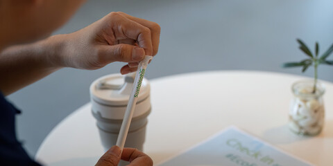 Sustainable and Responsible Choices. An individual holding a sustainable straw next to a reusable...