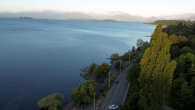 Aerial: Ranco Lake shore near Lago Ranco with a road at sunset in Ranco Province, Los Rios Region, southern Chile, push in pan drone shot