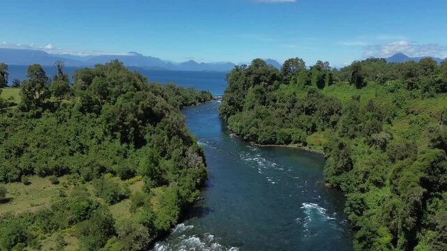 Aerial: Ranco Lake near Lago Ranco during the day with forest, mountains and blue sky in Ranco Province, Los Rios Region, southern Chile, push in tilt down drone shot