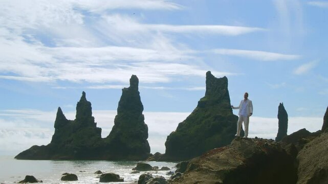 Sea stacks at Vik, Iceland, under a blue sky, attract nature lovers and photographers. This spot offers adventure, stunning sunsets, wildlife, and a peaceful atmosphere for enriching experiences