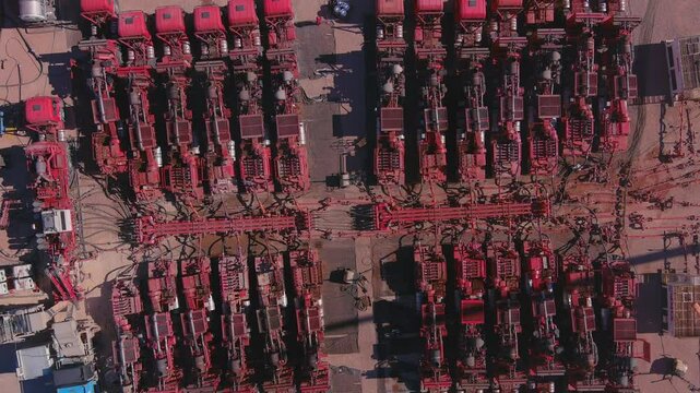 Trucks with high-pressure pumps work to break up the rock and obtain the shale oil. Drone goes up and captures the fracking set in Vaca Muerta