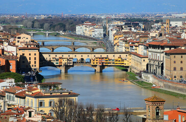 Obraz premium OLD BRIDGE called Ponte Vecchio over the Arno river perfectly illuminated by the sun and other historic buildings in florence in ITALY