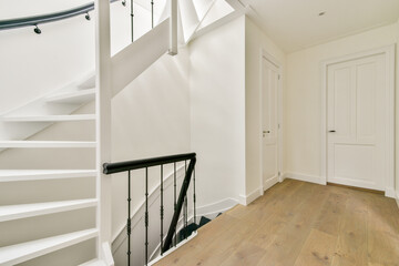 A clean and modern staircase leads to a bright hallway featuring minimalist decor. The light wood flooring complements the subtle white walls.