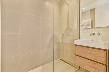 A stylish modern shower room featuring a glass enclosure, sleek tiles, and a wooden vanity. It's designed for contemporary living with a blend of elegance and functionality.