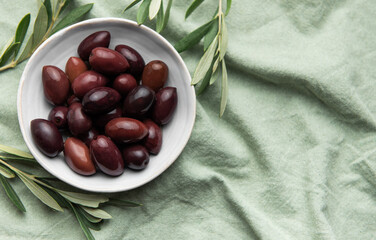 Bowl of fresh olives on green fabric background