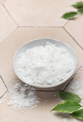 Magnesium chloride flakes in a bowl for spa treatment on tiled surface