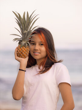 Close up portrait of girl holding pineapple in front of her face. Tropical fruit concept. Smiling face. Lifestyle. Bali.