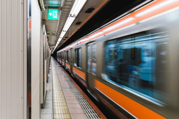 High-speed train arriving at a subway station in Tokyo, Japan. Motion blur captures the speed and efficiency of Japan’s railway system, a vital part of urban commuting and travel experience.