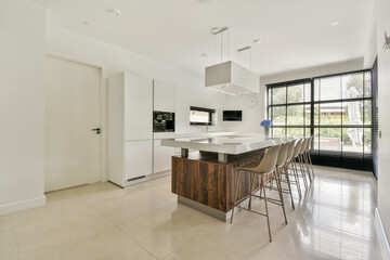 A sleek and contemporary kitchen featuring an elegant island, minimalist cabinetry, and ample natural light streaming through large windows.