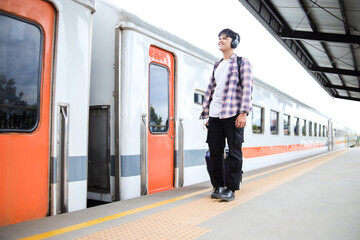 Asian Traveler Man Standing on Railway Platform, Waiting for The Train While Pulling Suitcase