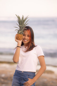 Teenager girl holding pineapple in front of her face. Tropical fruit concept. Smiling face. Lifestyle. Bali island.