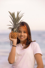 Close up portrait of girl holding pineapple in front of her face. Tropical fruit concept. Smiling face. Lifestyle. Bali.