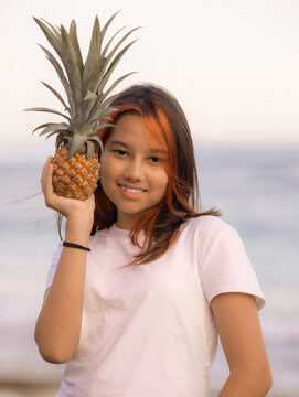 Close up portrait of girl holding pineapple in front of her face. Tropical fruit concept. Smiling face. Lifestyle. Bali.