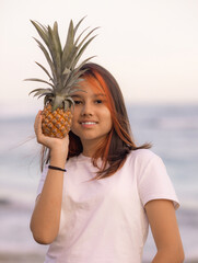 Close up portrait of girl holding pineapple in front of her face. Tropical fruit concept. Smiling face. Lifestyle. Bali.