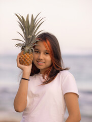 Close up portrait of girl holding pineapple in front of her face. Tropical fruit concept. Smiling face. Lifestyle. Bali.